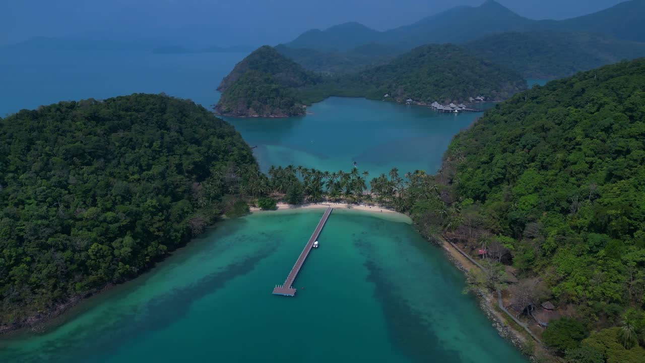 Koh Chang's idyllic landscape, featuring lush greenery, a pristine beach, and a tranquil pier extending into the turquoise waters. Beautiful aerial view flight panorama orbit drone