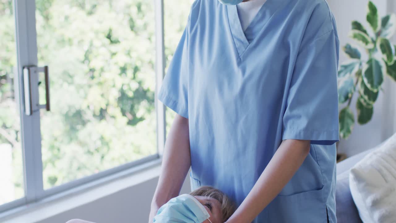 trabajadora de la salud masajeando el cuello de una mujer mayor en casa