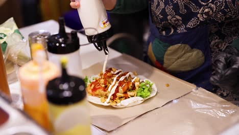 vendor adds sauce to doner kebab wrap