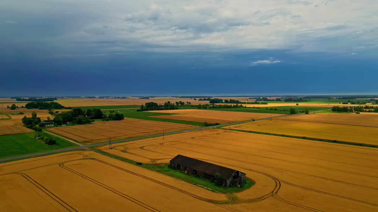 Aerial static shot of countryside driveway passing through agriculture fields during daytime