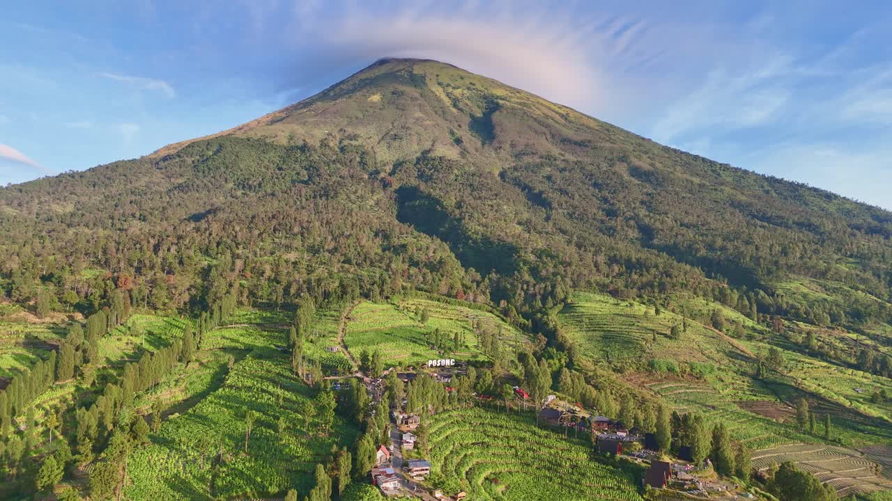 Aerial view of Posong Natural Park Tourist Destination on the slope of Mount Sindoro in the middle of green lush plantation. 4K drone shot of Indonesia rural landscape.
