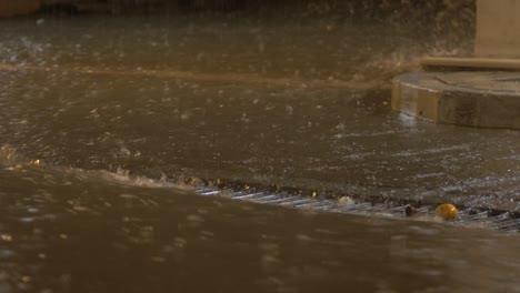 torrential rainfall flowing down street into drain