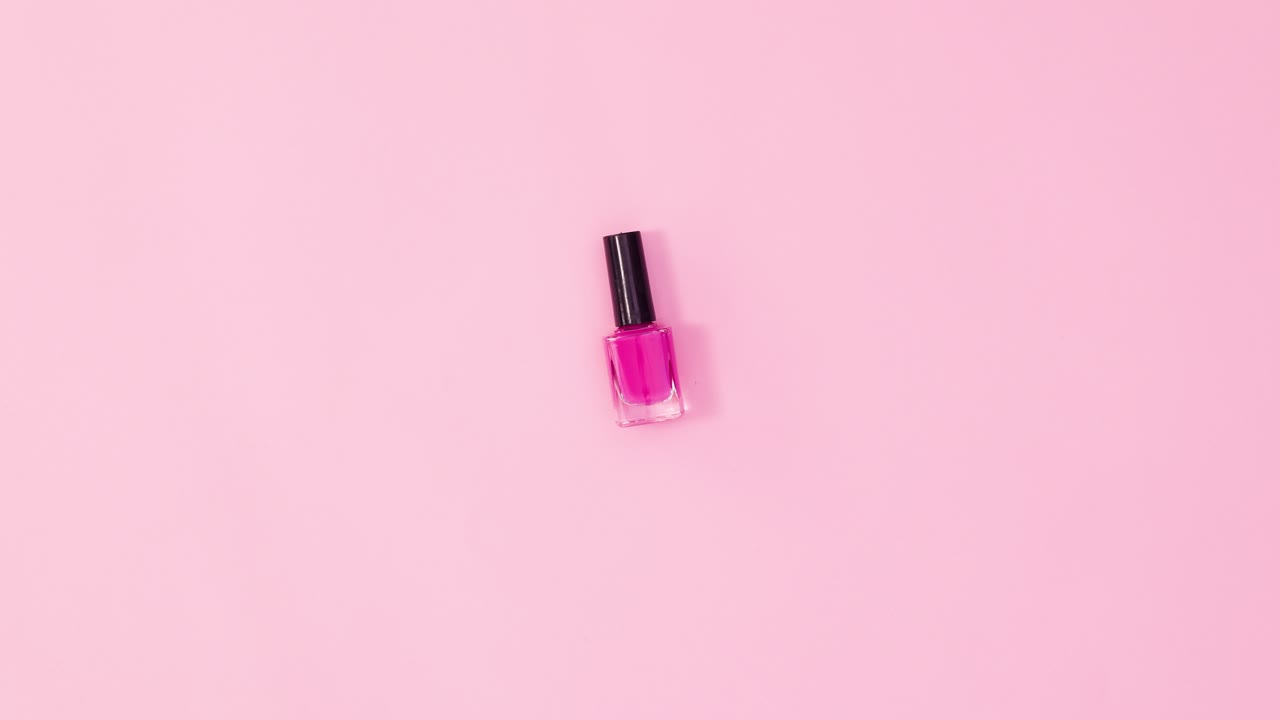 Manicure neglelakflaske roterende på pastelrosa baggrund. Stop motion flat lay