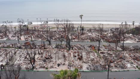 aerial low dolly shot of beachfront charred mobile homes after the palisades fire in los angeles, california. 4k