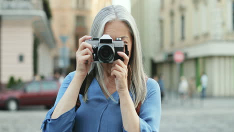 portrait of senior woman with long hair standing in front of the camera and taking photos