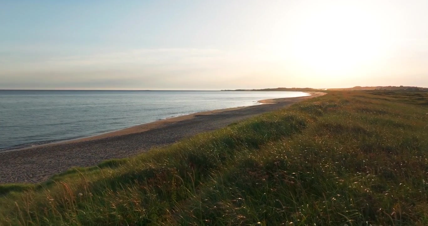 Droneoptagelse over kystklitter langs Brusand Strand ved solnedgang.