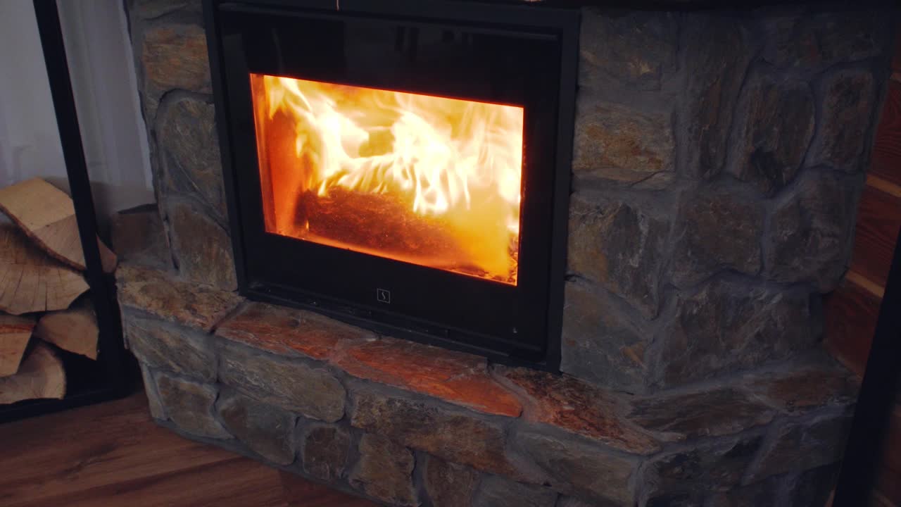 Close slider shot of a stone fireplace in a cosy wooden house.