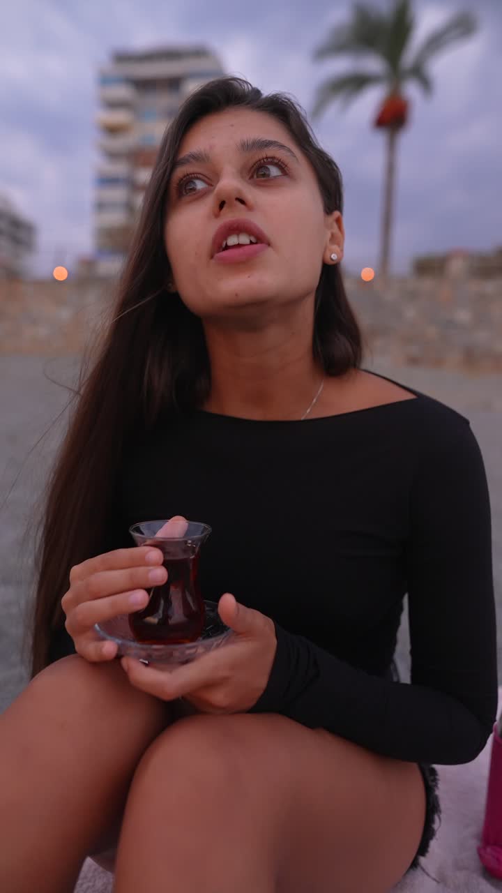 Mulher apreciando chá ao ar livre ao pôr do sol