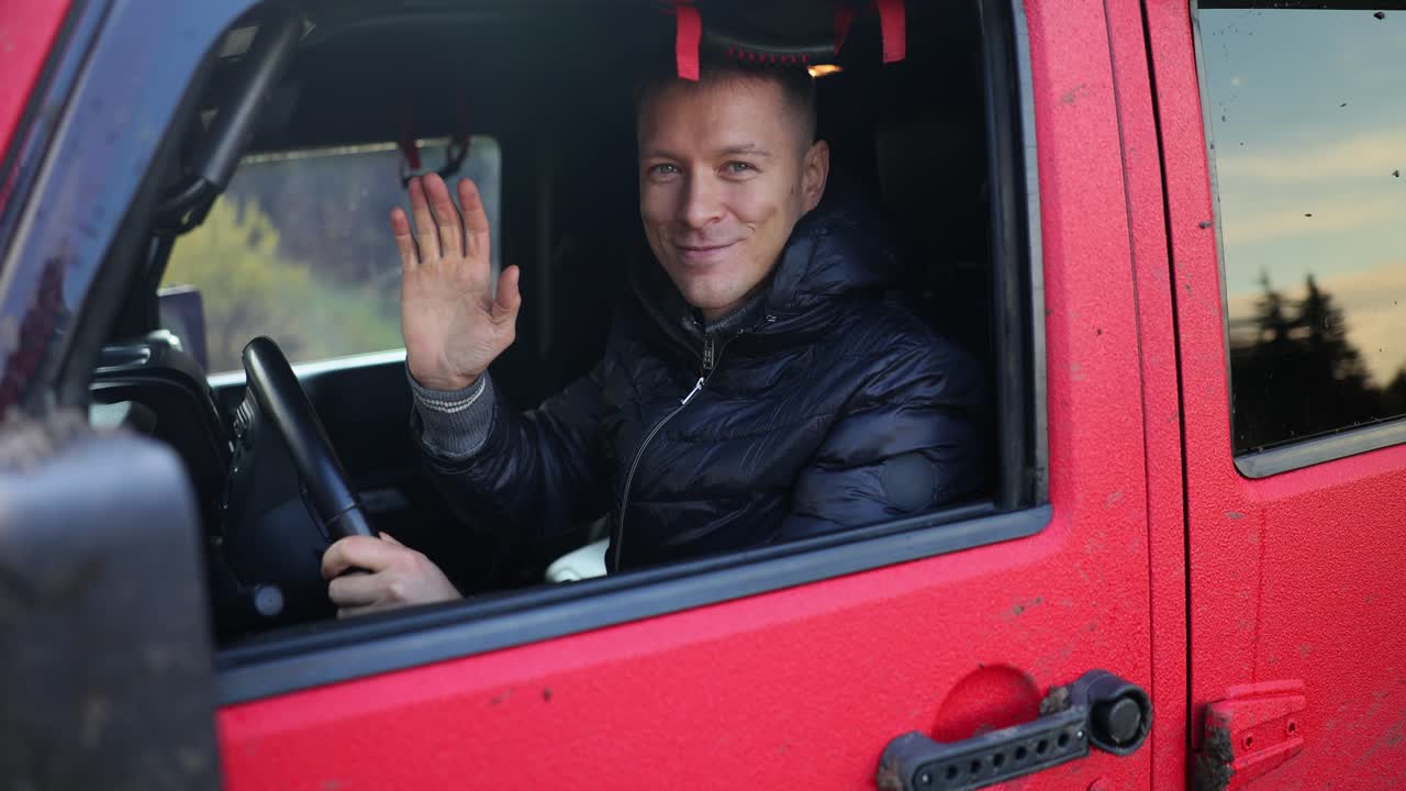Man Waving from Red Jeep