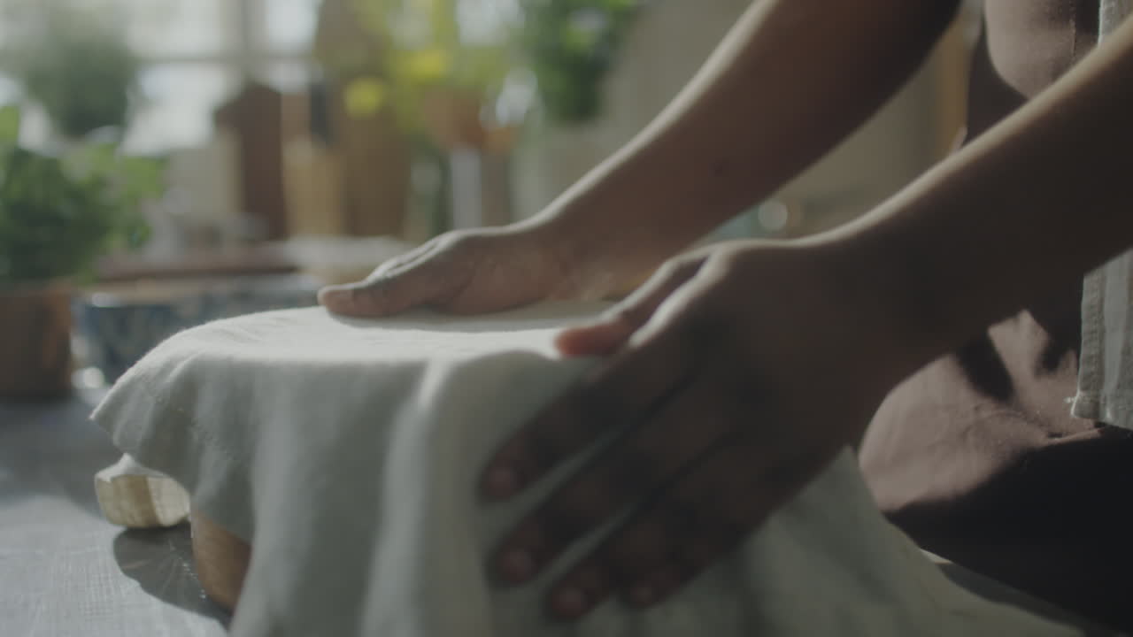 Baking preparation: Hands covering a bowl with a cloth