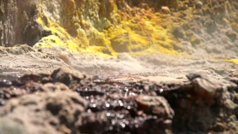 mineral liquid flowing on rocks with yellow sulfur in background, focus pull