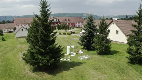 Altar-De-Boda-Blanco-Y-Sillas-En-La-Boda-De-La-Finca,-Tiro-Amplio-Aéreo