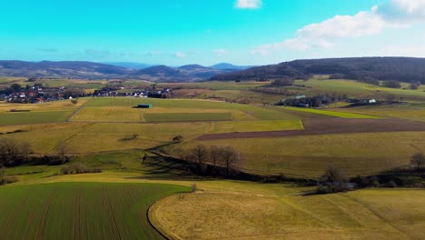 Sweeping-Aerial-View-of-Patchwork-Farmland-and-a-Quaint-Village