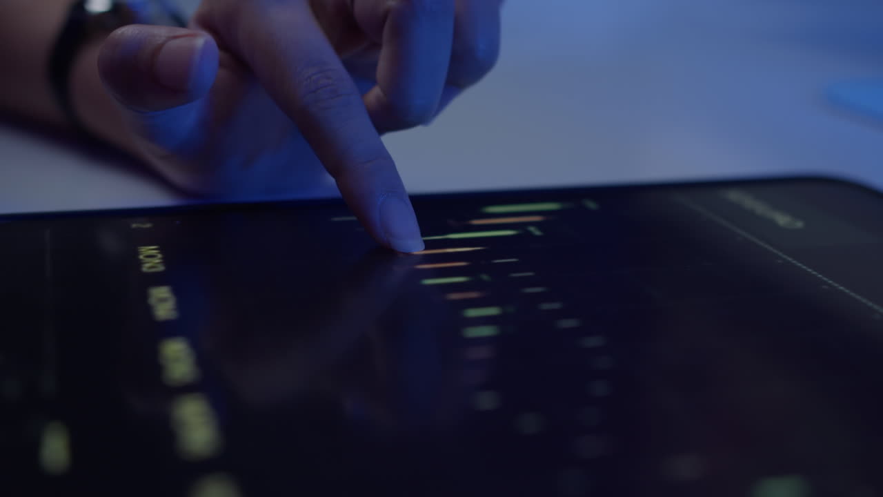 Hand of User Examining Chart on Tablet in Neon