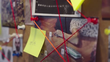 Handheld-shot-of-evidence-board-with-photos,-string,-pins,-and-connected-evidence