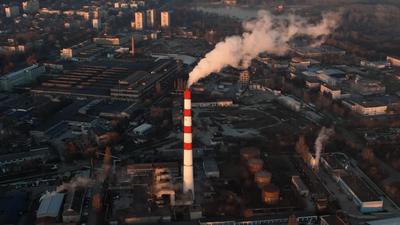Aerial drone view of thermal power plant in Chisinau at sunrise, Moldova. View of pipe with felling steam, cityscape