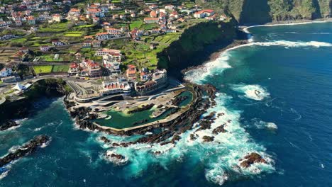 órbita-De-Drones-Alrededor-De-Piscinas-Naturales-Y-La-Ciudad-De-Porto-Moniz,-Costa-De-Madeira-Portugal-En-Un-Día-Soleado