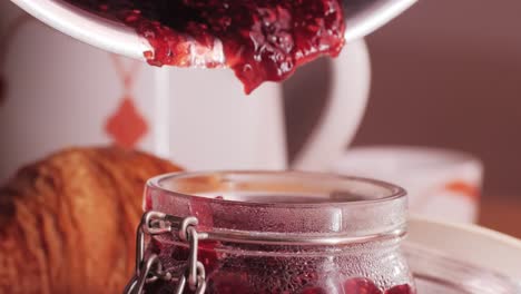 pouring homemade raspberry jam into a jar