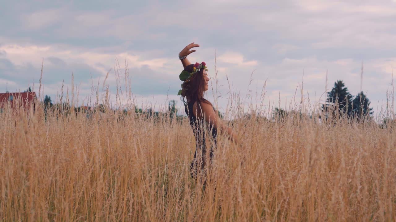 una chica muy joven y feliz bailando, disfrutando del hermoso clima y sintiendo el verano en los campos de cereales en la naturaleza