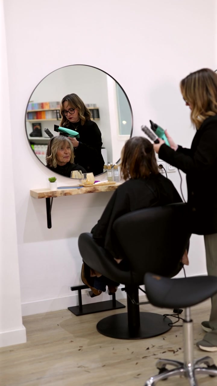 Cabeleireiro Profissional Secando o Cabelo da Cliente em Salão Moderno.