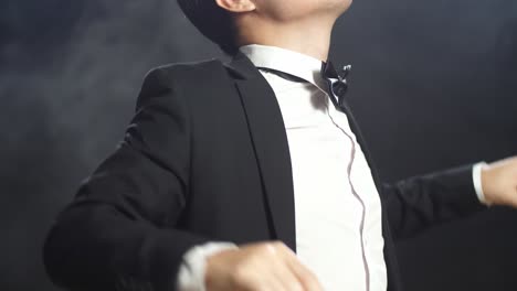 close up side view of asian conductor man holding a baton closing his eyes and showing gesture quickly in the black studio with fog