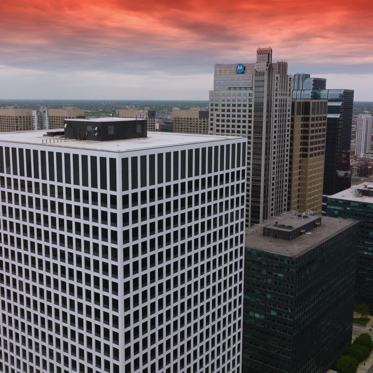 Flying over the buildings and among the skyscrapers of Chicago downtown. Amazing architecture of metropolis under the red sky