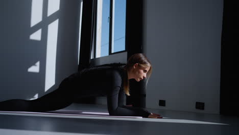 woman doing yoga stretch on a mat in a studio