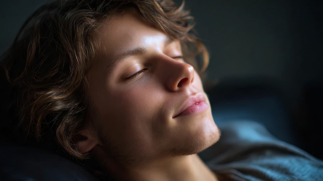 Serene Moment of Rest: A Young Man Peacefully Dreaming in a Dimly Lit Room, Capturing the Essence of Tranquility and Inner Calm Through His Resting Expression