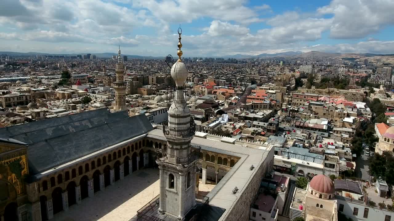 Aerial view around the minaret of the Umayyad Mosque in Syria. Drone is flying around the minaret with the city of Damascus in the background.