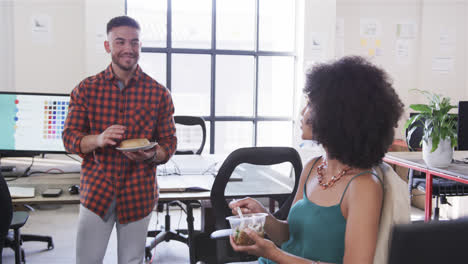 Happy-diverse-male-and-female-colleagues-having-lunch-break-in-office-and-talking,-slow-motion