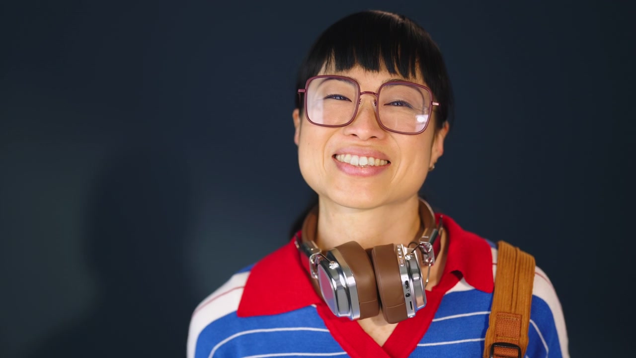 Smiling Young Woman With Headphones and Glasses Looking at Camera