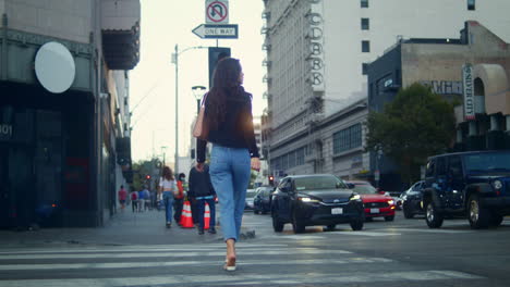 unrecognized woman walking on crossroad big city. unknown girl crossing road.