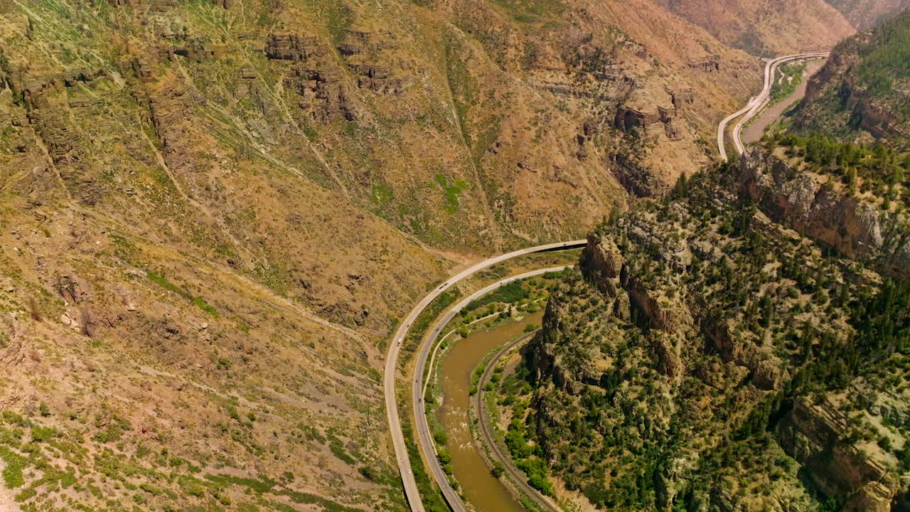 Scenic picture of mountainous area. Speed highways going along the narrow river between mountains. Aerial view.