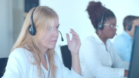 una operadora de centro de llamadas femenina seria poniéndose los auriculares