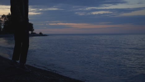 Man-Standing-On-The-Beach-Shore-And-Taking-Photos-On-The-Calm-Sea-During-Sunset-Time