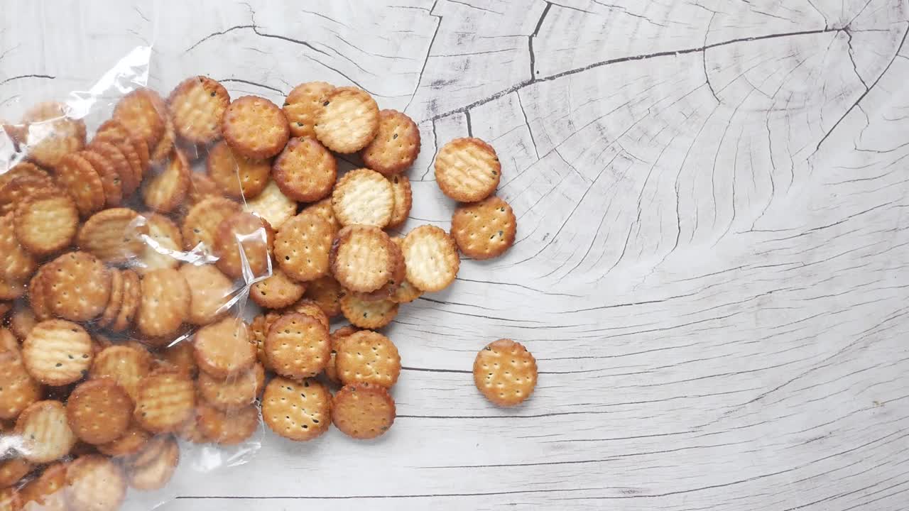 Small Round Crackers in Plastic Bag on Wooden Table