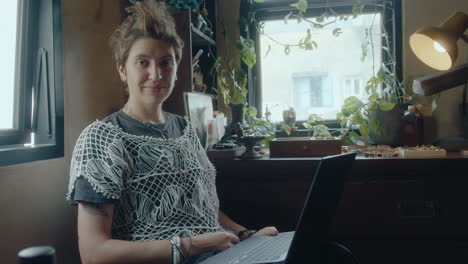young woman with laptop posing for camera in antiques store