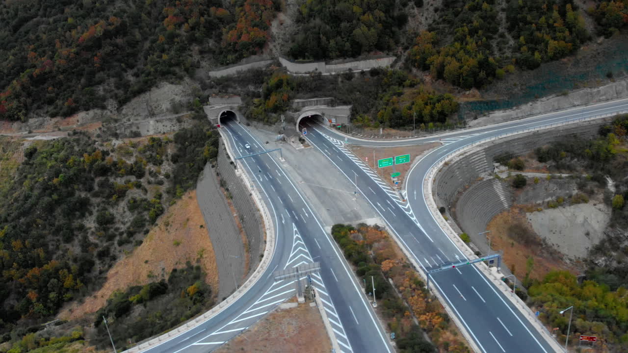 Túneles de autopista atraviesan un terreno montañoso, mostrando infraestructura moderna en medio de un paisaje natural. Ideal para temas de transporte e ingeniería.