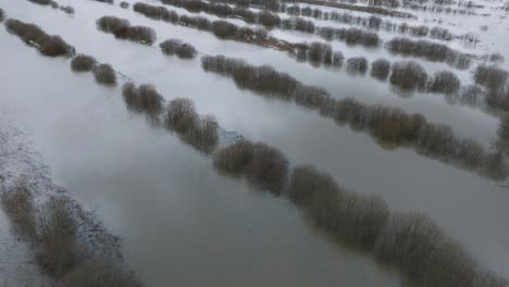 vista aérea de aguas altas en primavera, inundación del río alande, agua marrón y fangosa, campos agrícolas bajo el agua, día nublado, disparo de drone de ojo de pájaro amplio hacia adelante