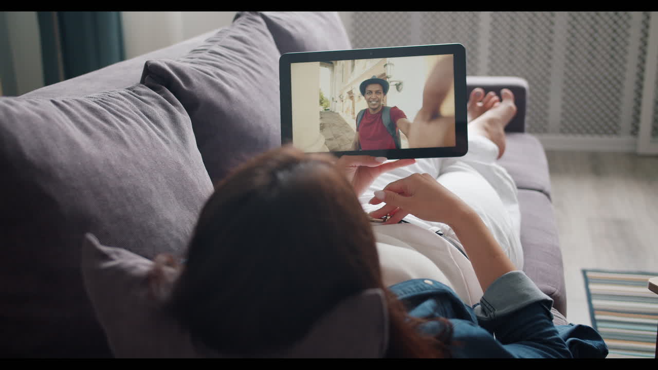 Donna in videochiamata con un uomo mentre si rilassa sul divano