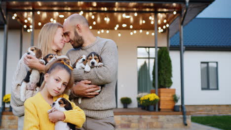 family portrait - a young couple with a child and a puppies in front of their house