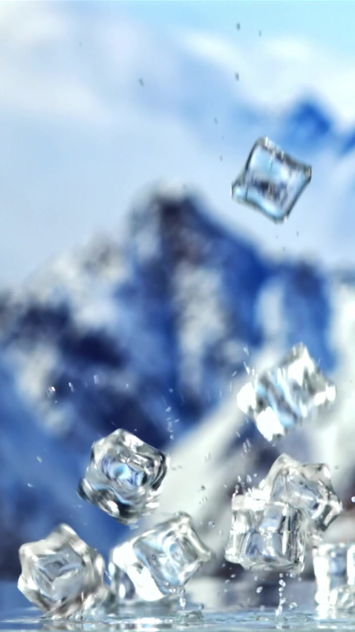 Cubetti di ghiaccio trasparenti che cadono nell'acqua con uno sfondo di montagna innevata