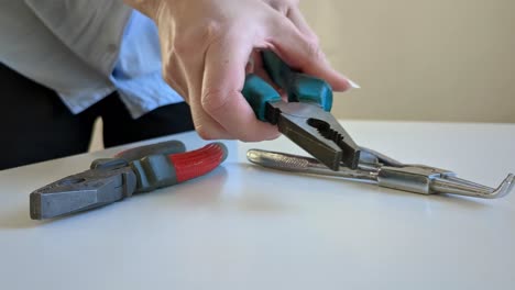 woman grabbing pliers, variety of pliers on desktop