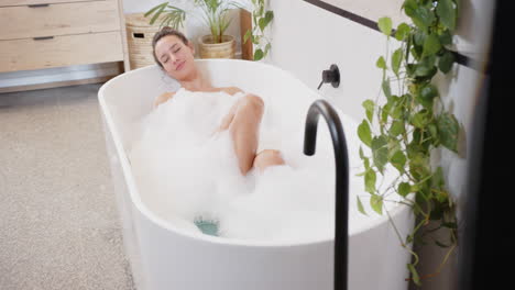 relaxing in bathtub, woman enjoying bubble bath in modern bathroom home