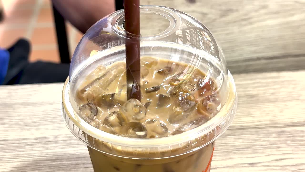 나무 테이블 에서 얼음 커피 를 맛보고 있다