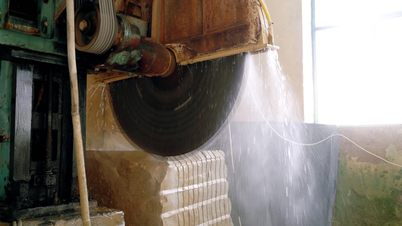 an automatic equipment with water dispenser is cutting a huge stone with a steel disc. Stone processing technology