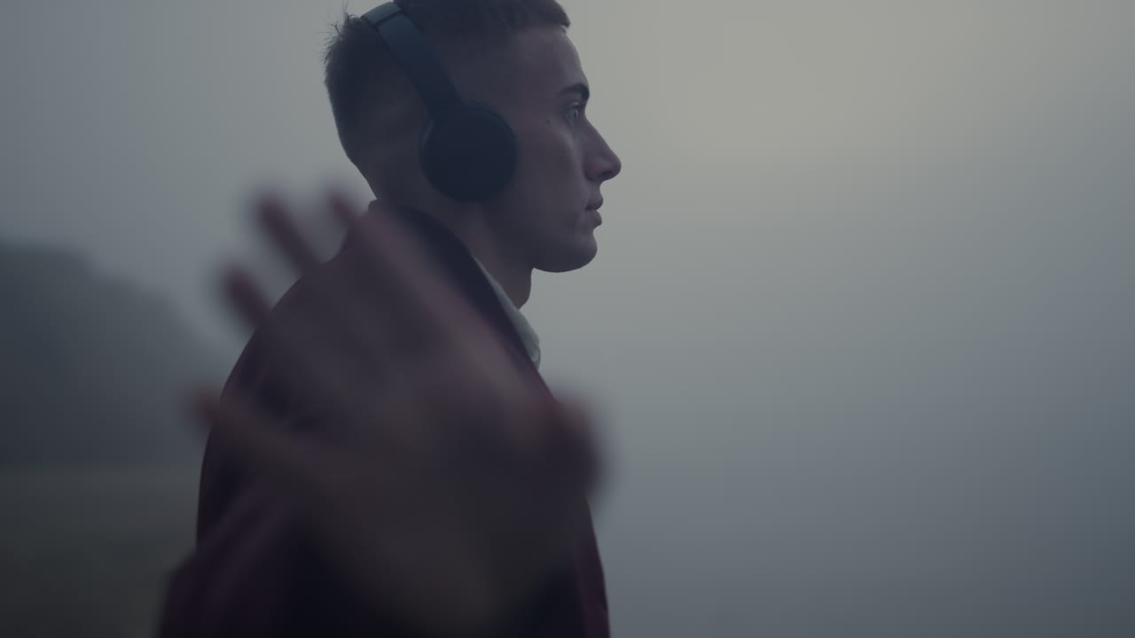 Inspired man dancing headphones on beach. Guy listening music in earphones