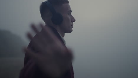 inspired man dancing headphones on beach. guy listening music in earphones