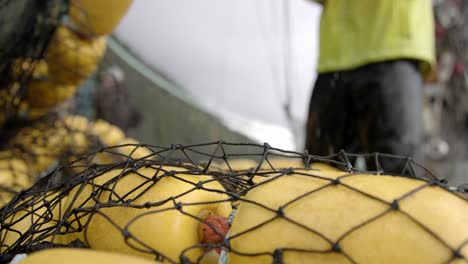 fisherman sets fishing net with floats on boat deck, close up slowmotion