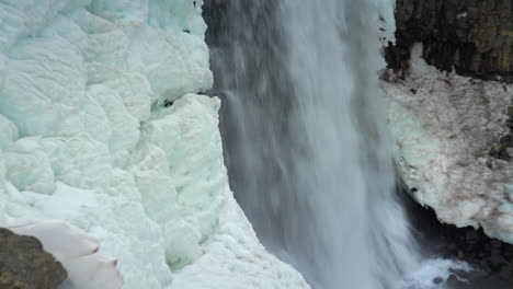 cascada de agua a través de un acantilado de columna de basalto helado
